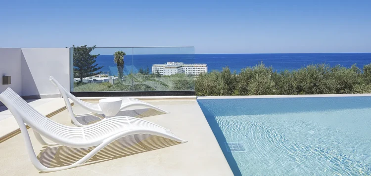 Białe leżaki Vondom Ibiza przy basenie infinity nad morzem