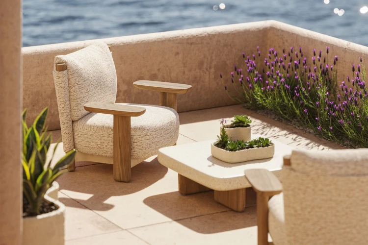 Kremowy fotel Vondom Milos Wood Lounge na tarasie z widokiem na ogród